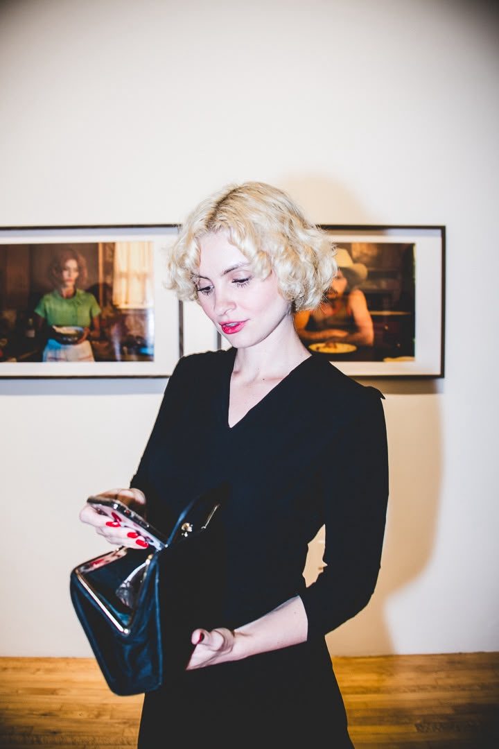 Guest at the Interval Gallery opening night, framed photographic works on the wall behind