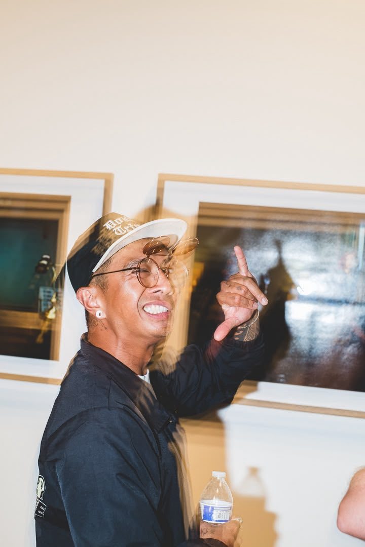 Visitor gesturing toward framed photographs hung along the gallery wall